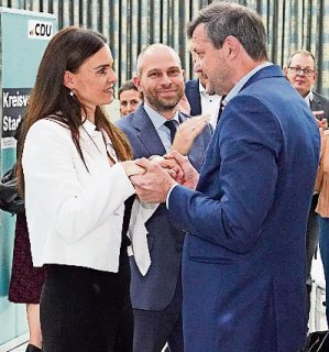 Oliver Grundmann im blauen Jackett gratuliert Vanessa-Kim Zobel im weißen Blazer. Im Hintergrund applaudiert Eike Holsten.